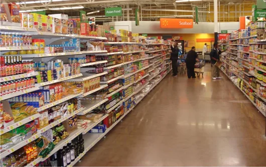 A photo shows the interior of a grocery store aisle lined with shelves of packaged food, with a few shoppers browsing.